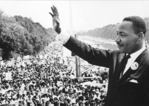 Black and white photo of Martin Luther King Jr. waving to a crowd at the Washington Monument in Washington DC